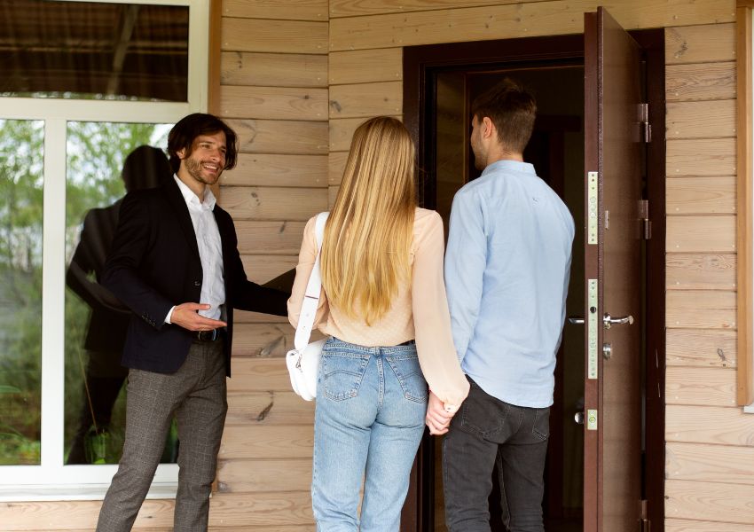 landlord ushering two prospective tenants into an available property